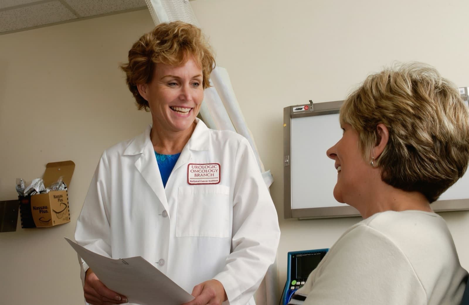 A clinician talks with a patient in an exam room.